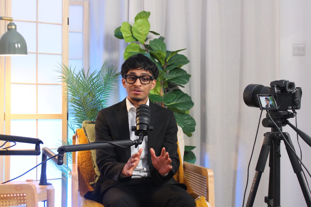 Guest gesturing while speaking into a microphone with a camera in frame