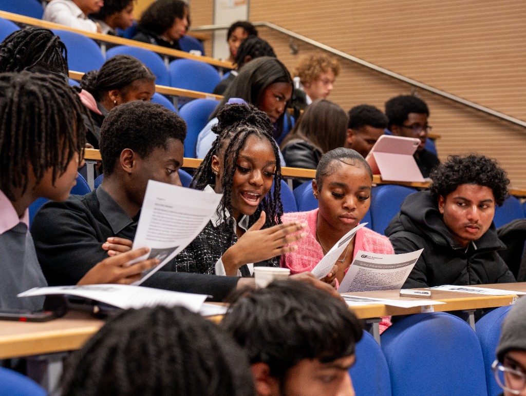 Investate members in a lecture hall working together on application materials